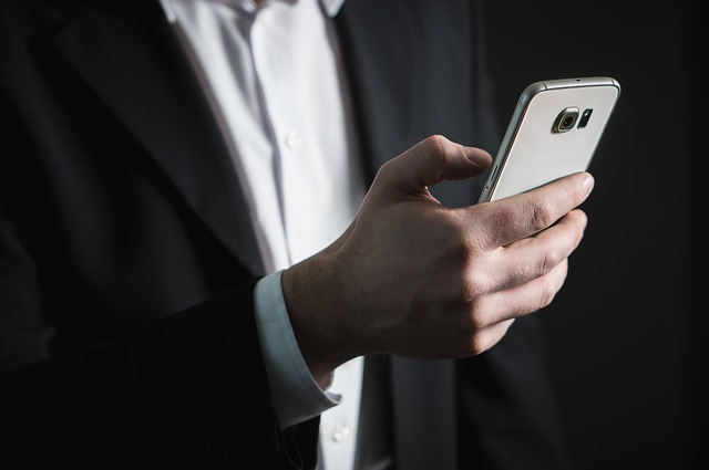 片手でスマホを持っている男性の写真