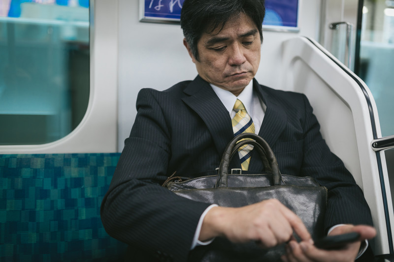 通勤中にスマホを見る男性