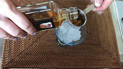氷の入ったグラスにウィスキーを注ぐ様子