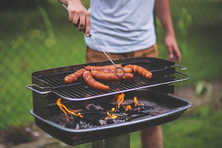 コンロでソーセージを焼く男性