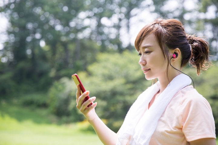 運動中にイヤホンで音楽を聴く女性