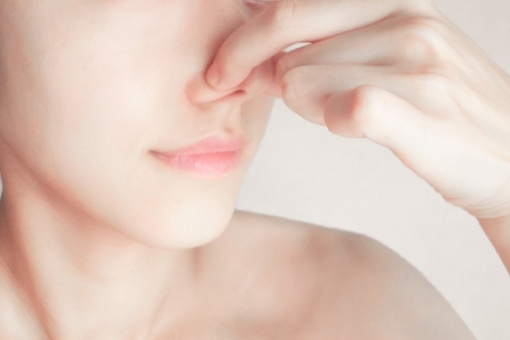 鼻をつまむ女性の写真