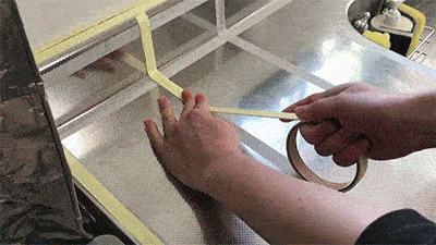キッチンのワークトップに両面テープを貼っている様子