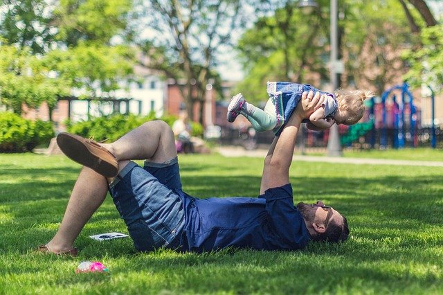 芝生に寝そべる親子の写真