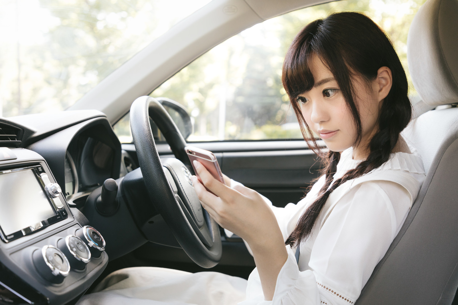 車でスマホを見る女