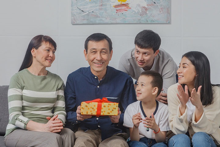プレゼントを手に持っている父親を囲む家族