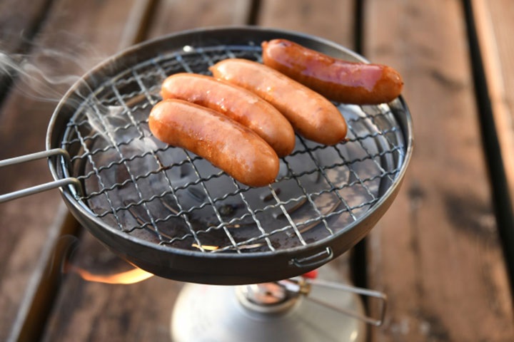 クッカーとバーナーでウィンナーを焼いている様子