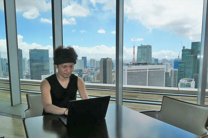 レジデンスのラウンジで作業する佐藤さん