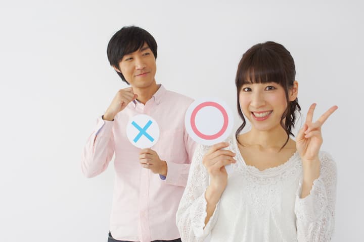 マルの札を持っている女性とバツの札を持っている男性