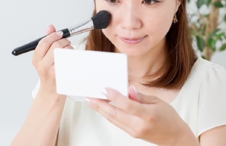 仕上げパウダーをブラシでつける女性