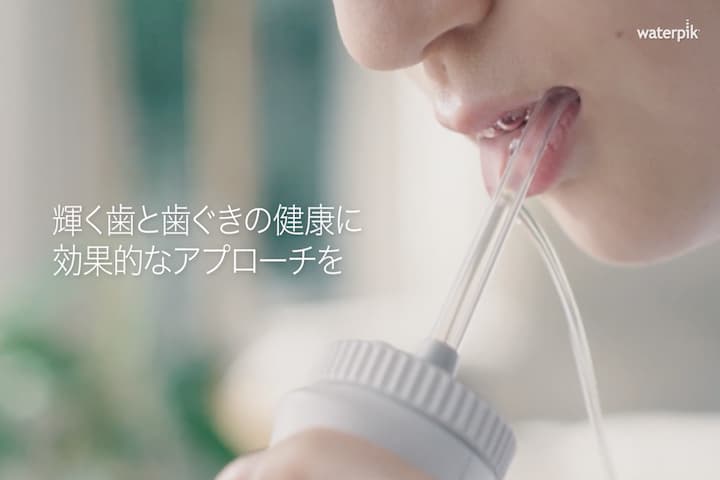 ウォーターピックを口の中に入れて使う女性の写真