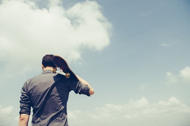 スケートボードを持つ男性の画像