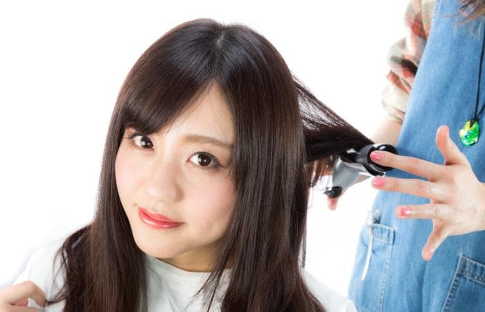 ヘアアイロンで髪を巻く女性