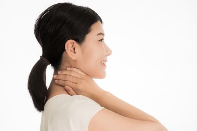 首に手をやる女性の画像