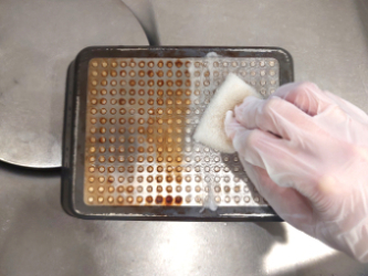 フライパンの裏側に重曹をぬってこする様子