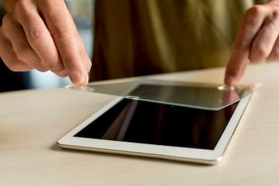 iPadとみられるタブレット端末に保護フィルムを貼り付けている様子